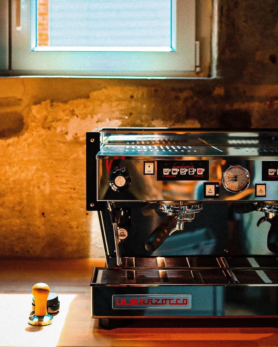 Zweigruppige Espressomaschine in warmem Licht, Detailaufnahme der Brühgruppen