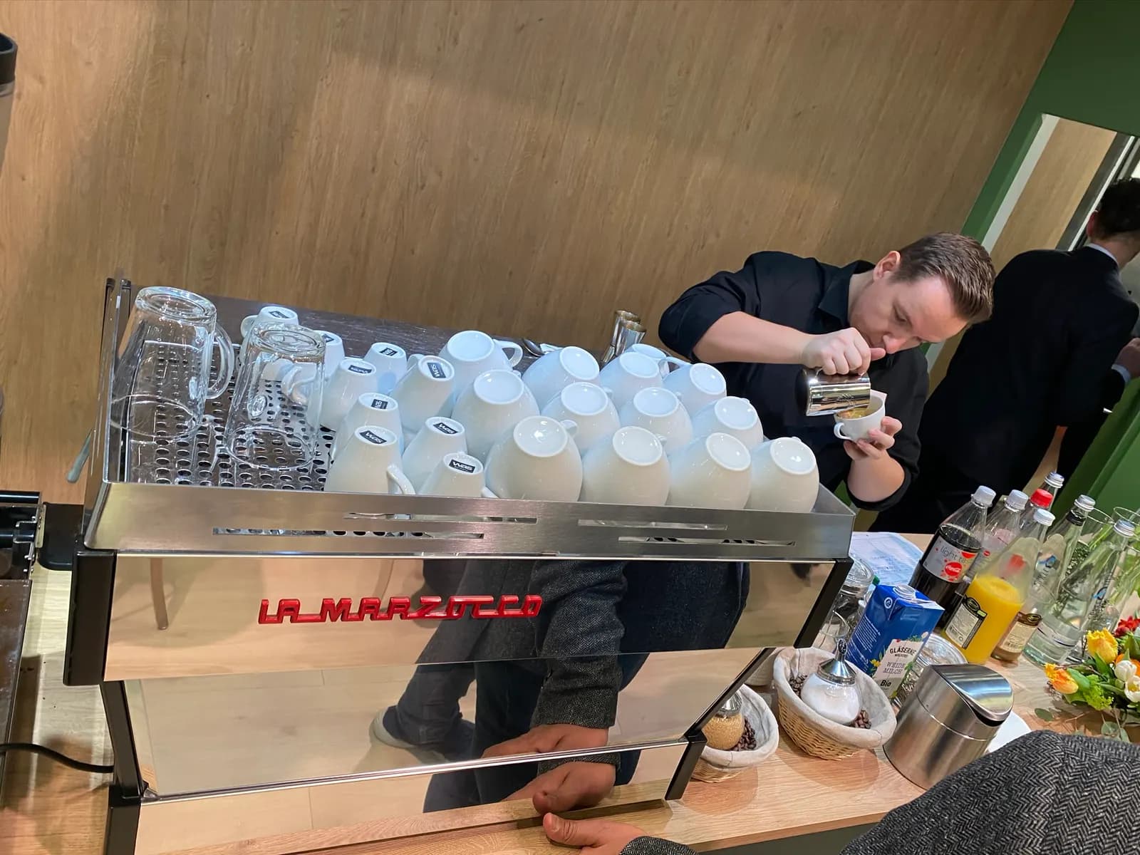 Barista an der Espressomaschine mit vorbereiteten Tassen