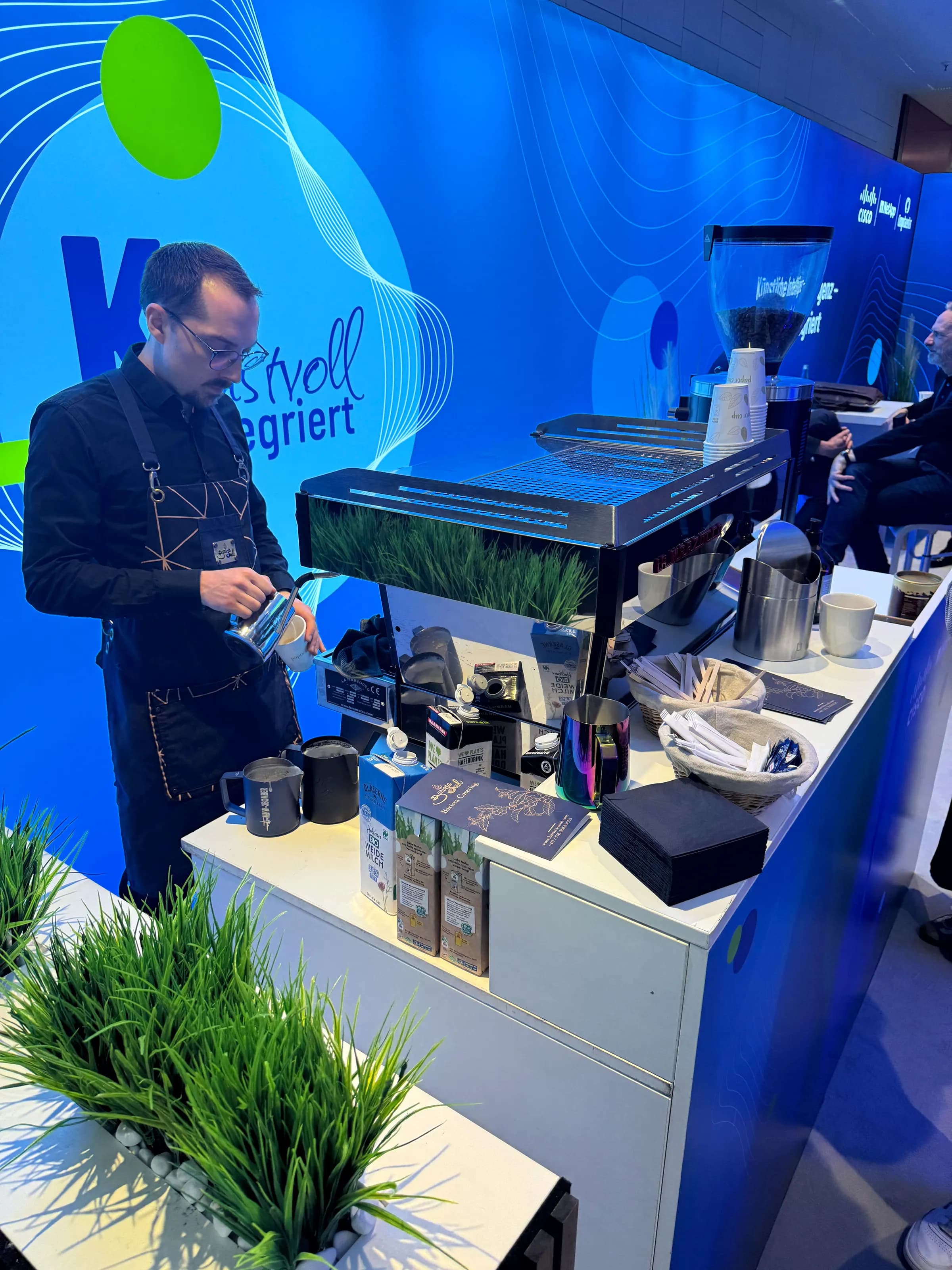 Barista bereitet an einem Messestand ein Milchgetränk zu